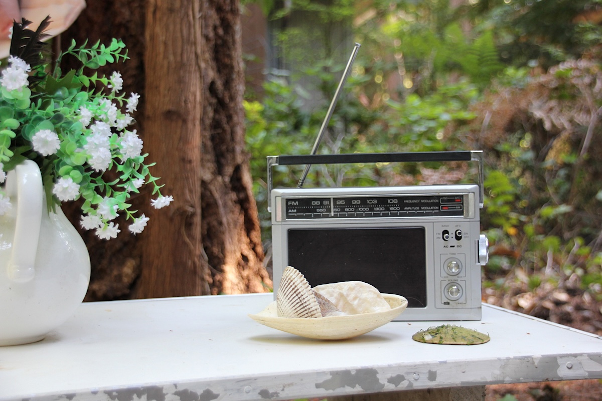 An AM radio sits on a table outside the cottage.