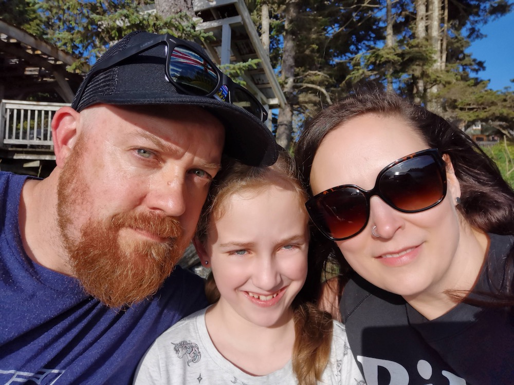 The Locke family poses outdoors. Photo features two white adults and one child, smiling at the camera. 