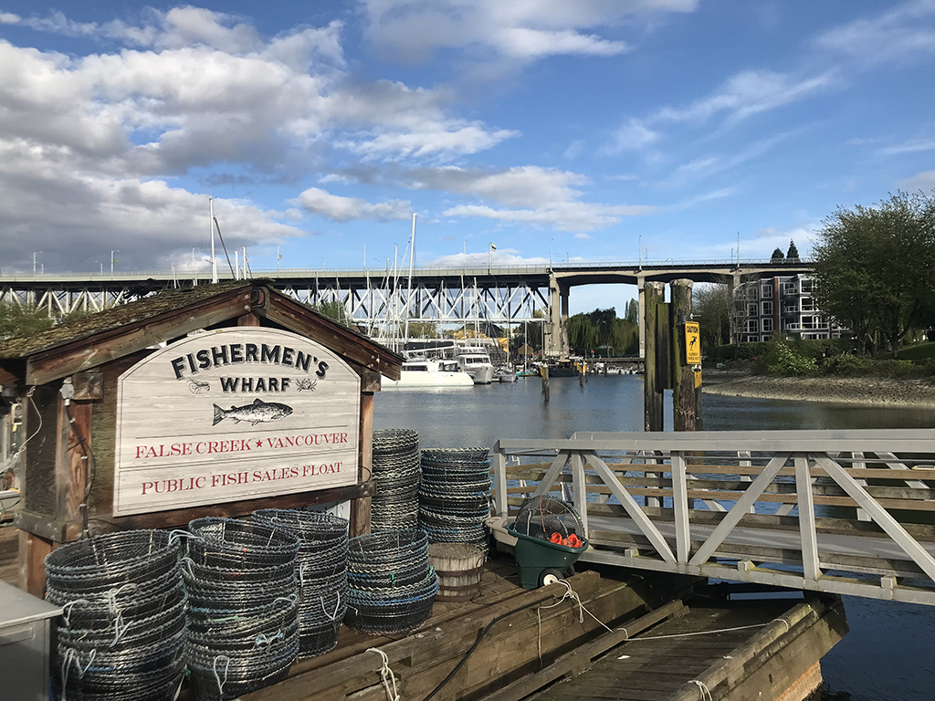 A sign reads &ldquo;Fisherman&rsquo;s Wharf, False Creek, Vancouver.&rdquo; In the background is Granville Bridge and False Creek. In the foreground, crab pots.