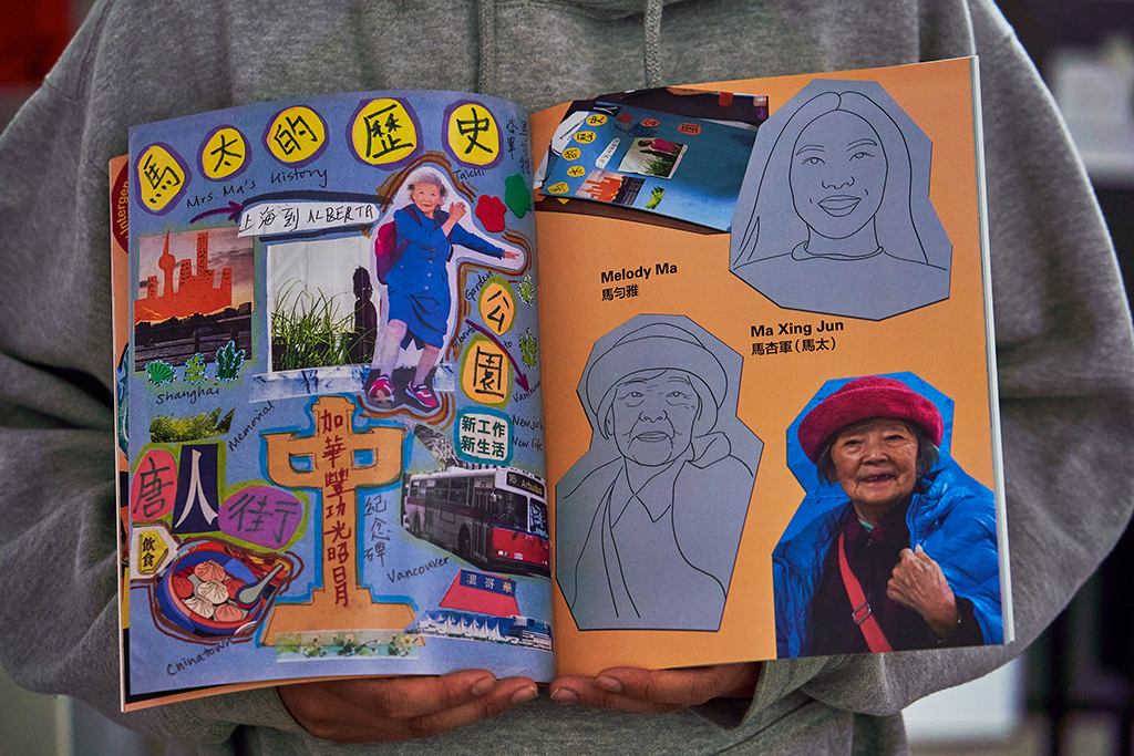 Beverly Ho is wearing a grey hoodie. We can’t see her face, but we can see her hands holding the zine with colourful handmade collage work about Xin Jun Ma.