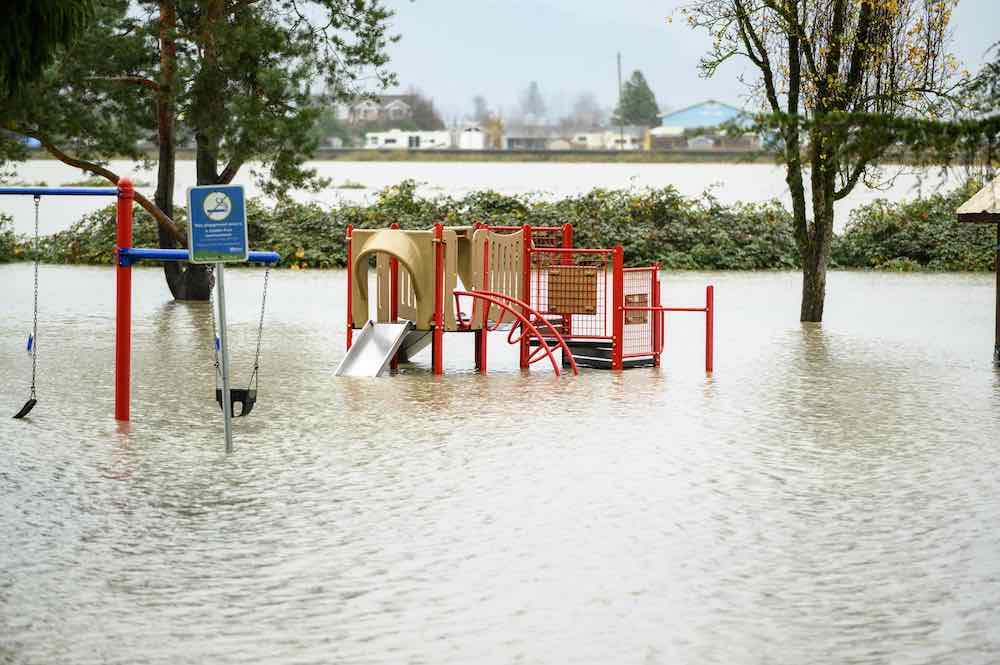 Floodwaters engulf a playground in Abbbotsford, B.C. on Nov. 18, 2021. Red climbing equipment and swings are visible above the water, but we can&rsquo;t see the ground.