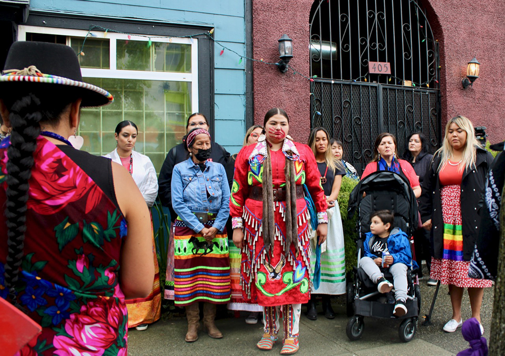 About dozen family members of Noelle O&rsquo;Soup, some in traditional regalia, gather outside the red-brick SRO where O&rsquo;Soup&rsquo;s body was found.