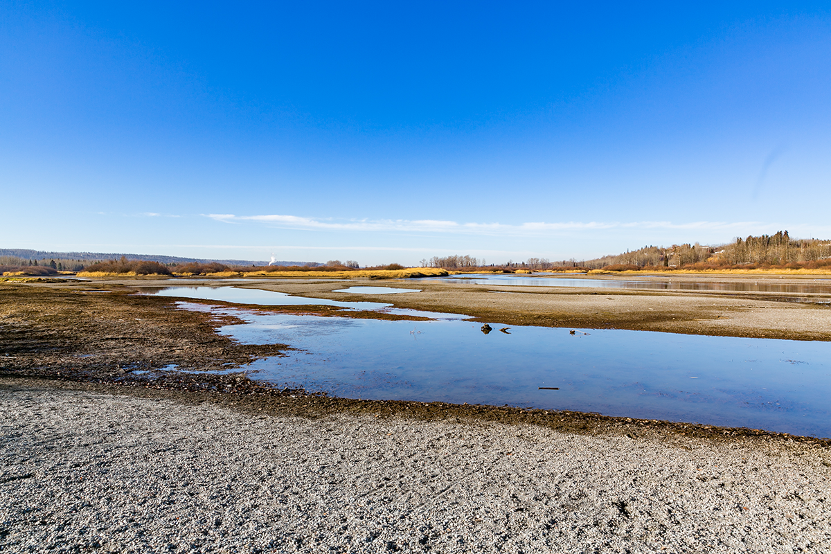 The Nechako River at low water level as a result of releases from the reservoir. The riverbed is largely dry, with sand and gravel bars exposed.