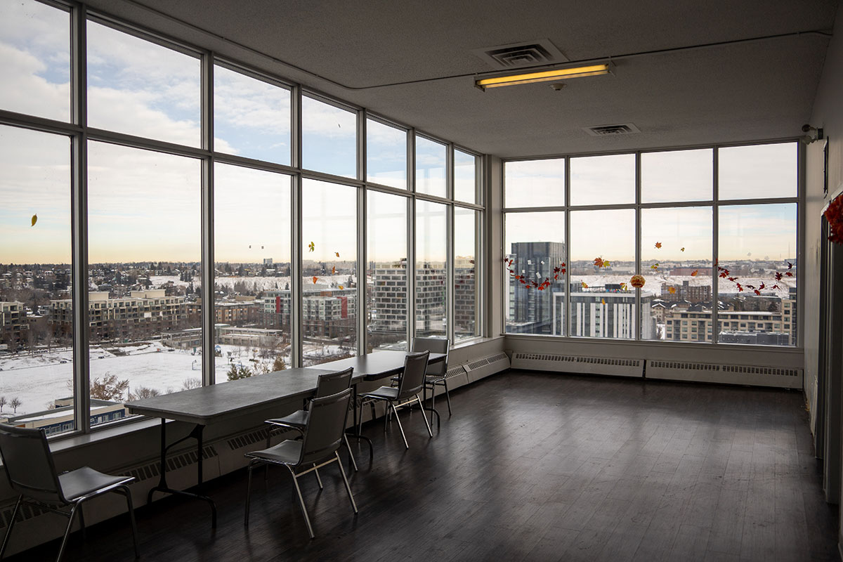 A room with floor-to-ceiling windows looks on to the Calgary skyline.