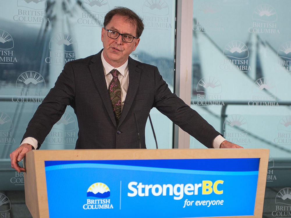 A man in a suit and a paisley tyee stands begin a podium.