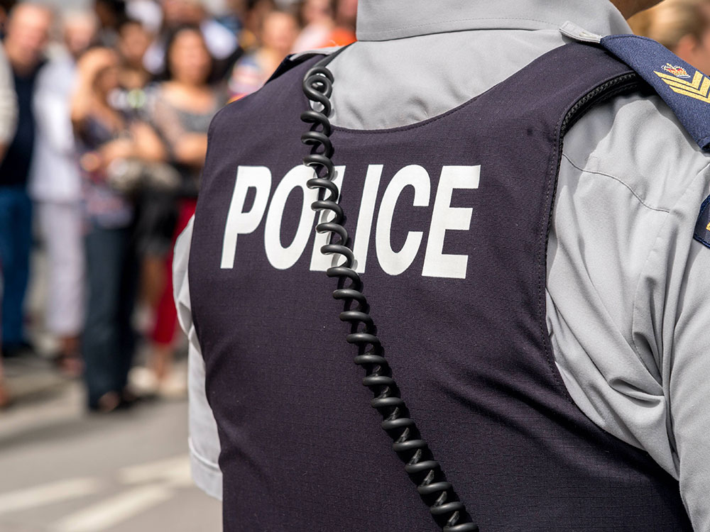 A closeup of an officer wearing a stab vest with &lsquo;Police&rsquo; across the back.