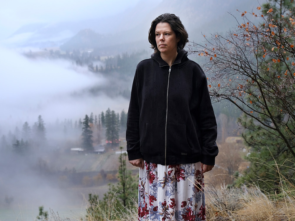 A woman standing on a hill, with a smokey valley below.