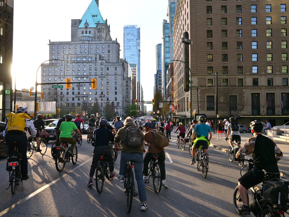 Dozens of cyclists are gathered and taking up lanes on West Georgia Street.