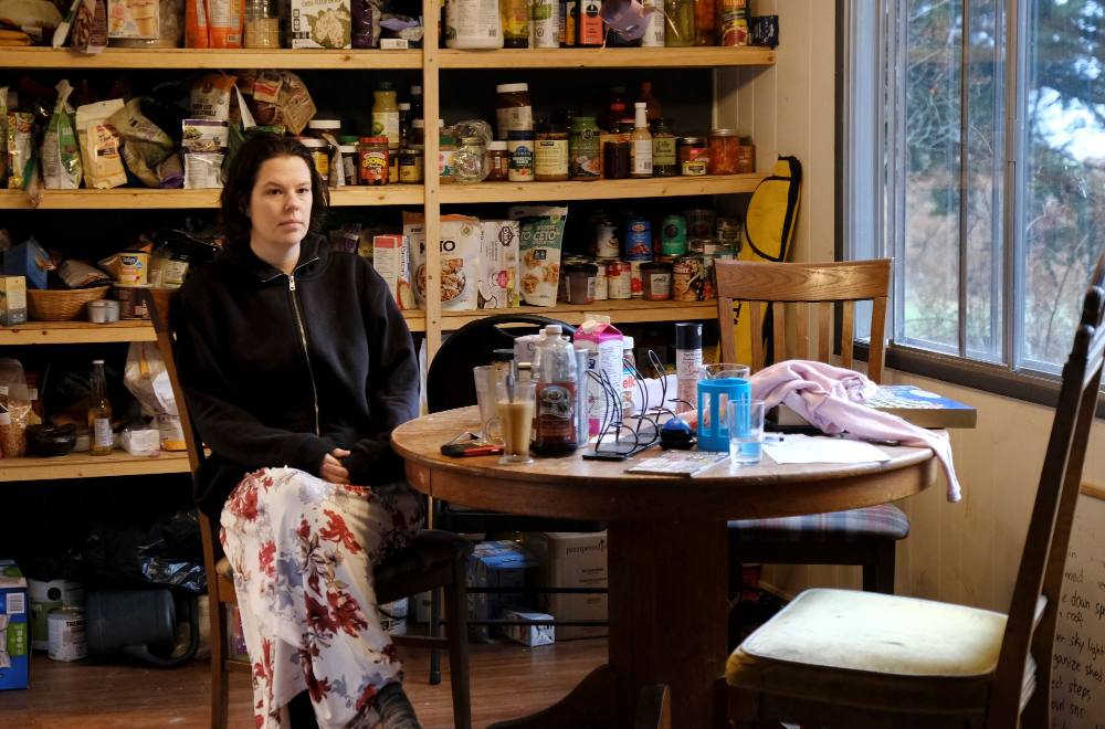 A woman wearing a hoodie sits at a table filled with breakfast items.