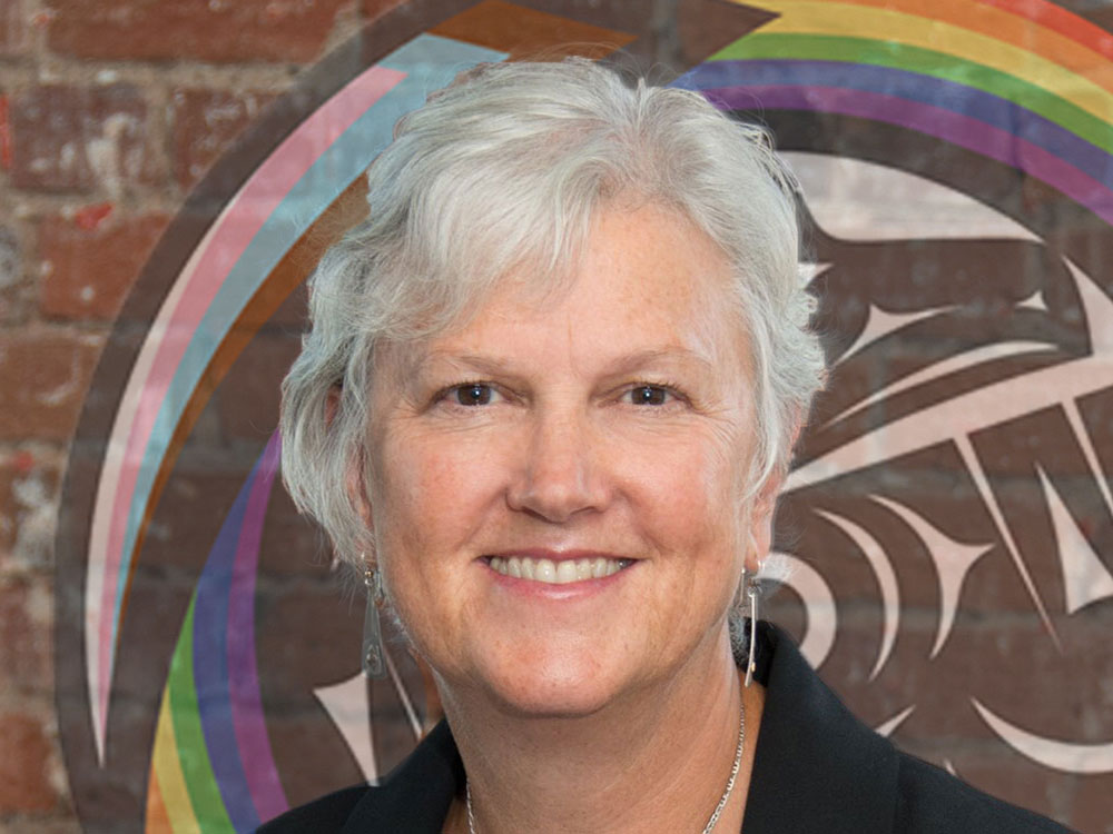 A portrait of a woman with grey hair wearing a blue shirt and blazer.