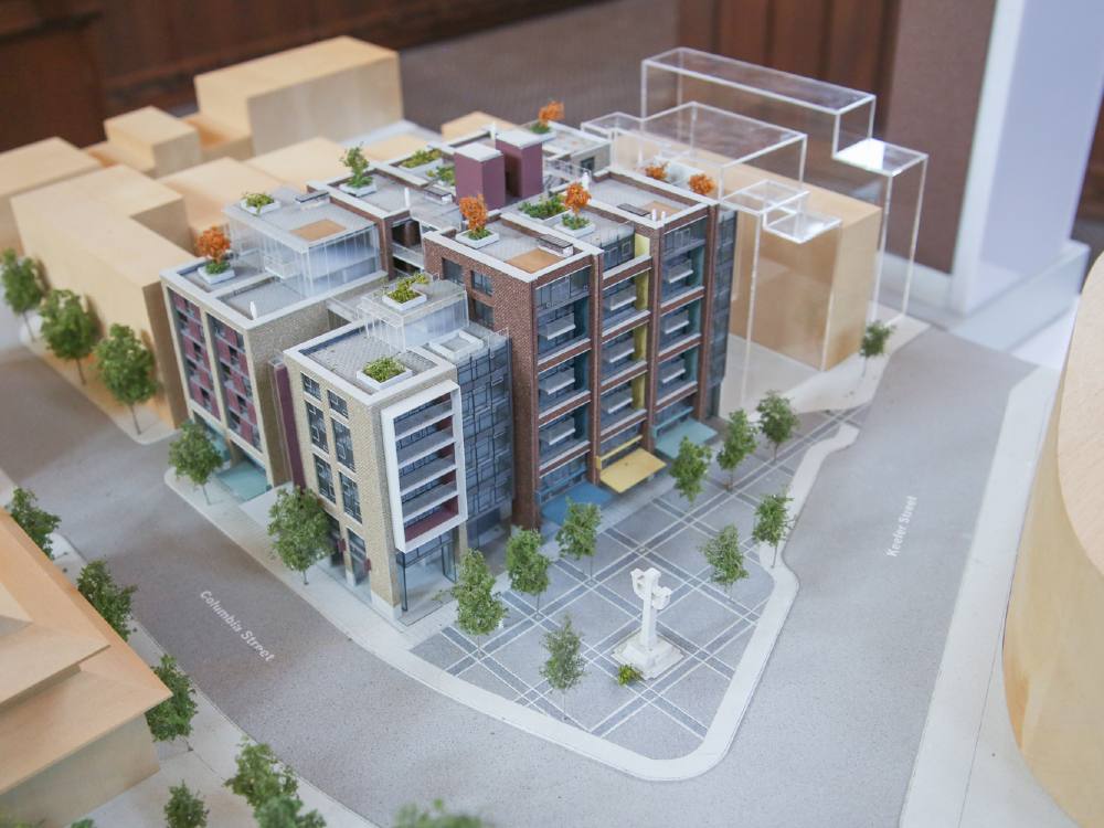 A model of a condo building in Vancouver&rsquo;s Chinatown, fronting a memorial plaza with a sculpture dedicated to railroad workers and veterans.