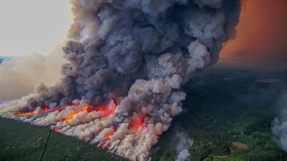 An aerial photo shows a huge fire, with large flames over a large area and billowing clouds of smoke.