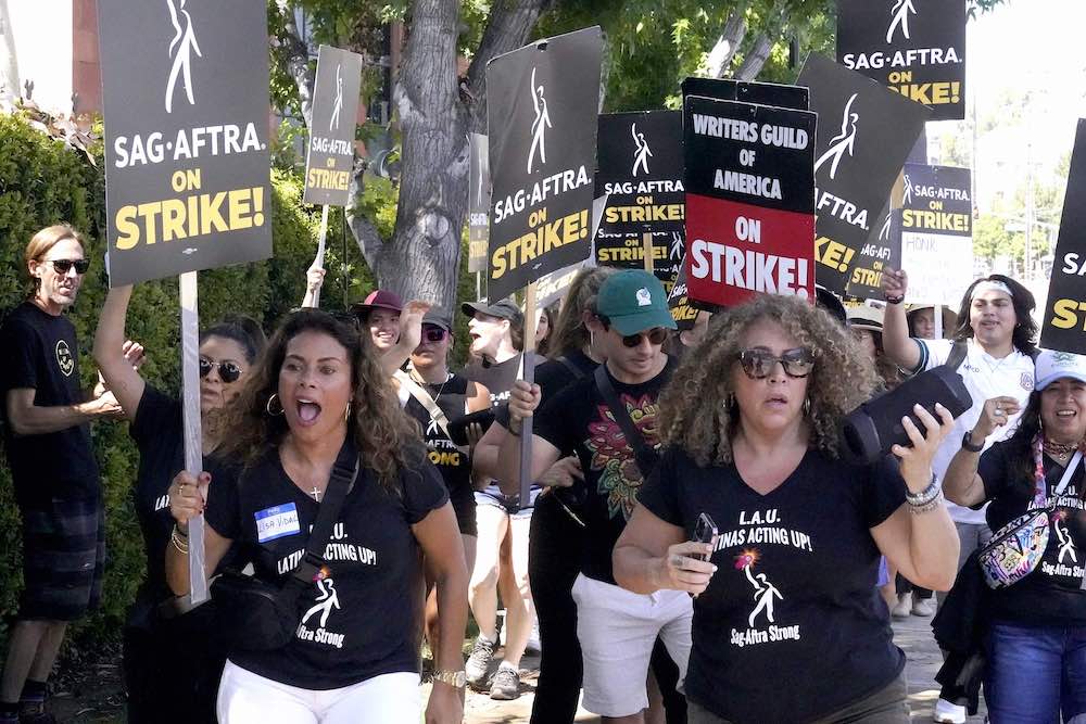 A group of protesters, led by two women, hold signs that say &ldquo;On Strike.&rdquo;