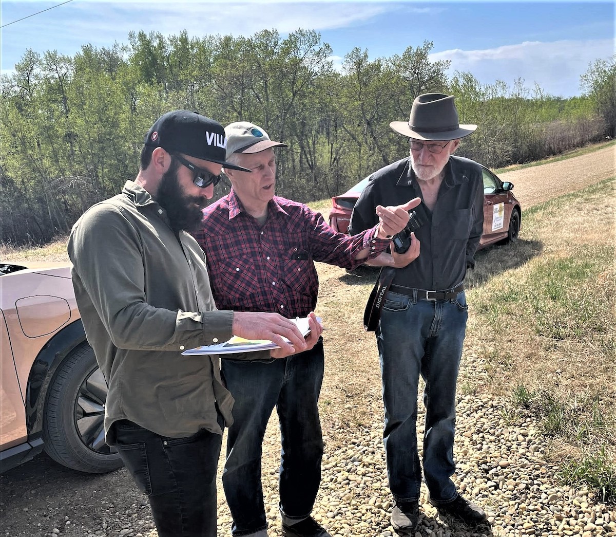 Three people survey outdoors.