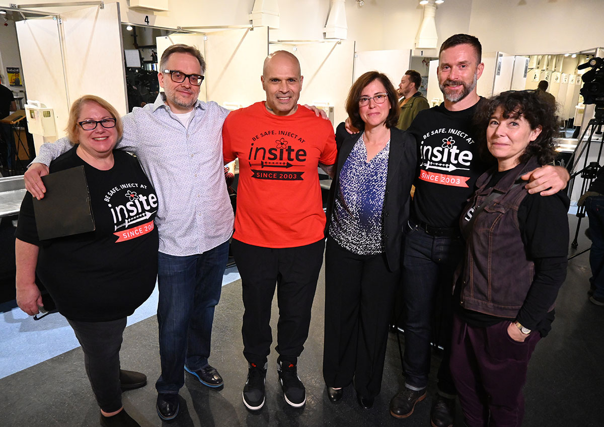 A group photo with six people. Some are wearing shirts that read &lsquo;Be Safe. Inject at Insite.&rsquo;