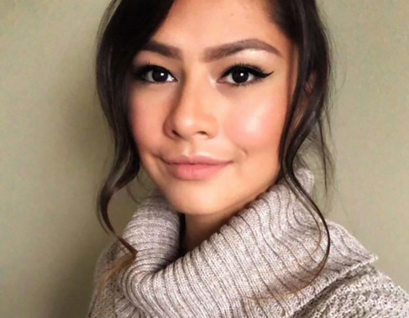 A young woman with dark hair partially pulled back smiles at the camera.