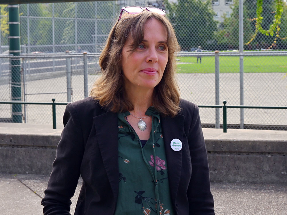 Sonia Furstenau, a light-skinned woman with shoulder-length dark brown hair, looks off-camera during an outdoor announcement.