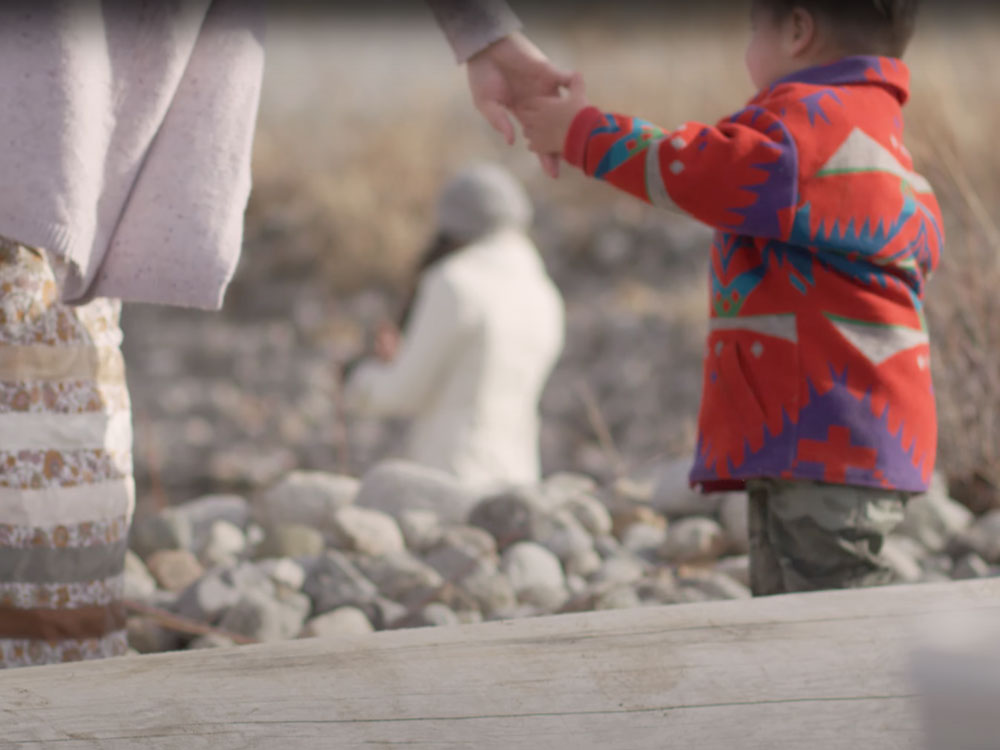 A child reaches up and holds their parent&rsquo;s hand.