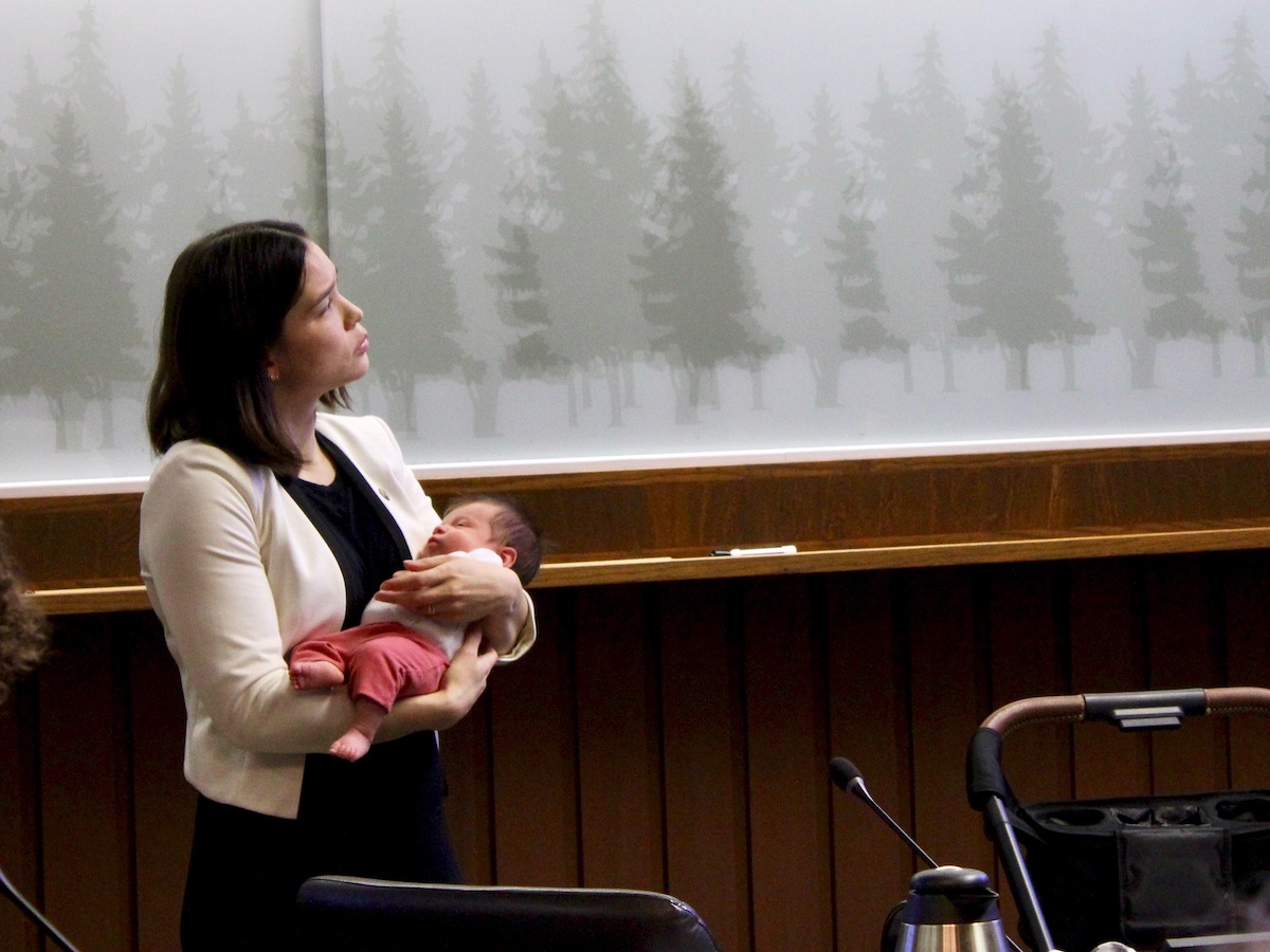 A woman with brown hair cradles a baby.
