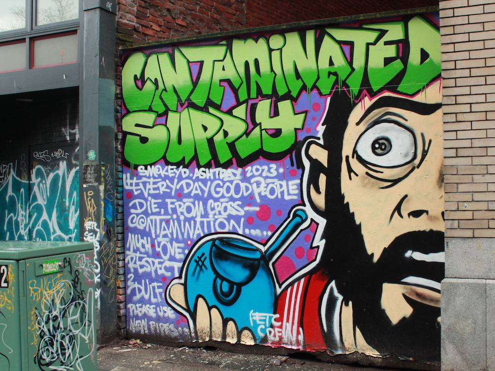 A mural reads 'Contaminated Supply. Smokey D. Ashtray 2023. Every day good people die, from cross-contamination.... Much love. Respect 2 DULF. Please use new pipes.'