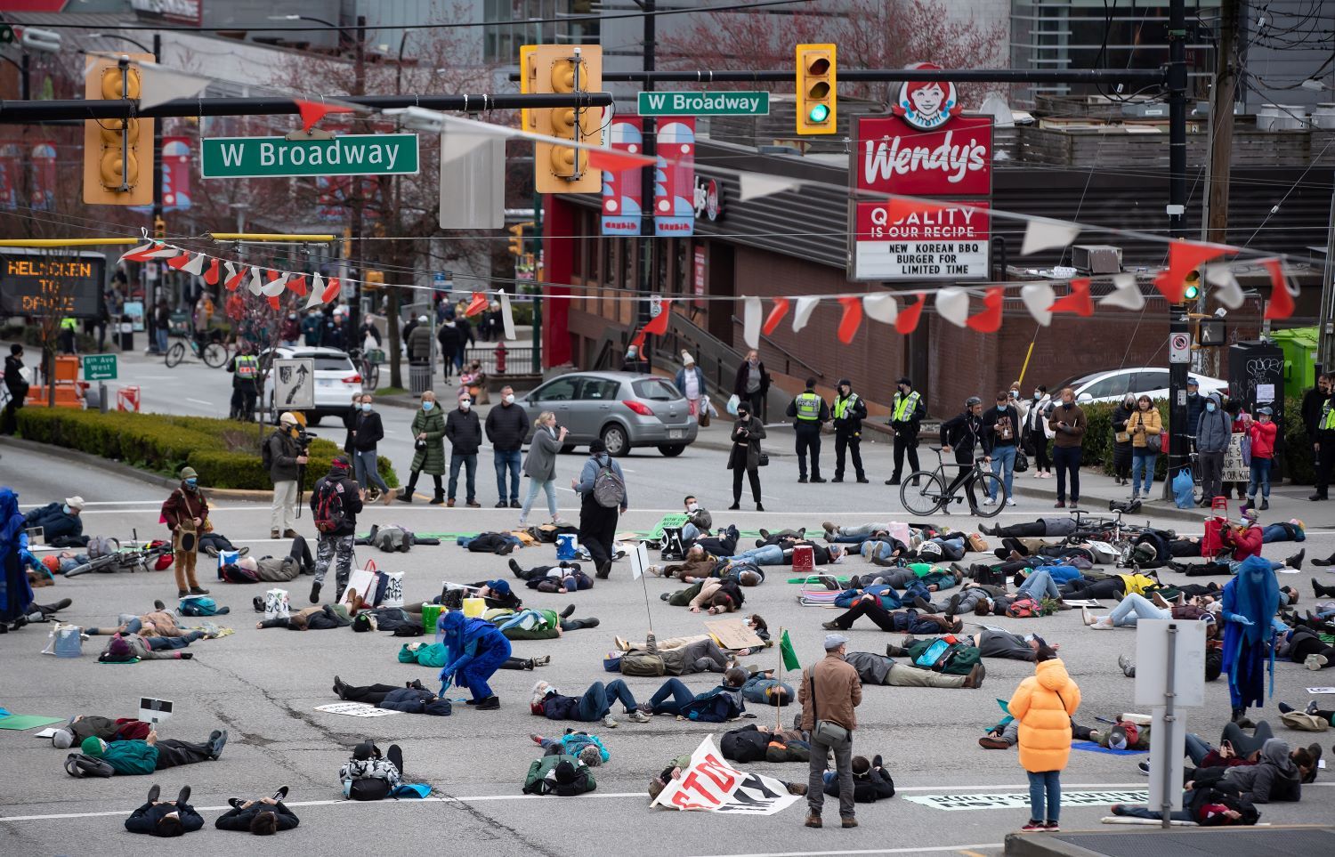 Dozens of people lie in the street in a protest on West Broadway in Vancouver.