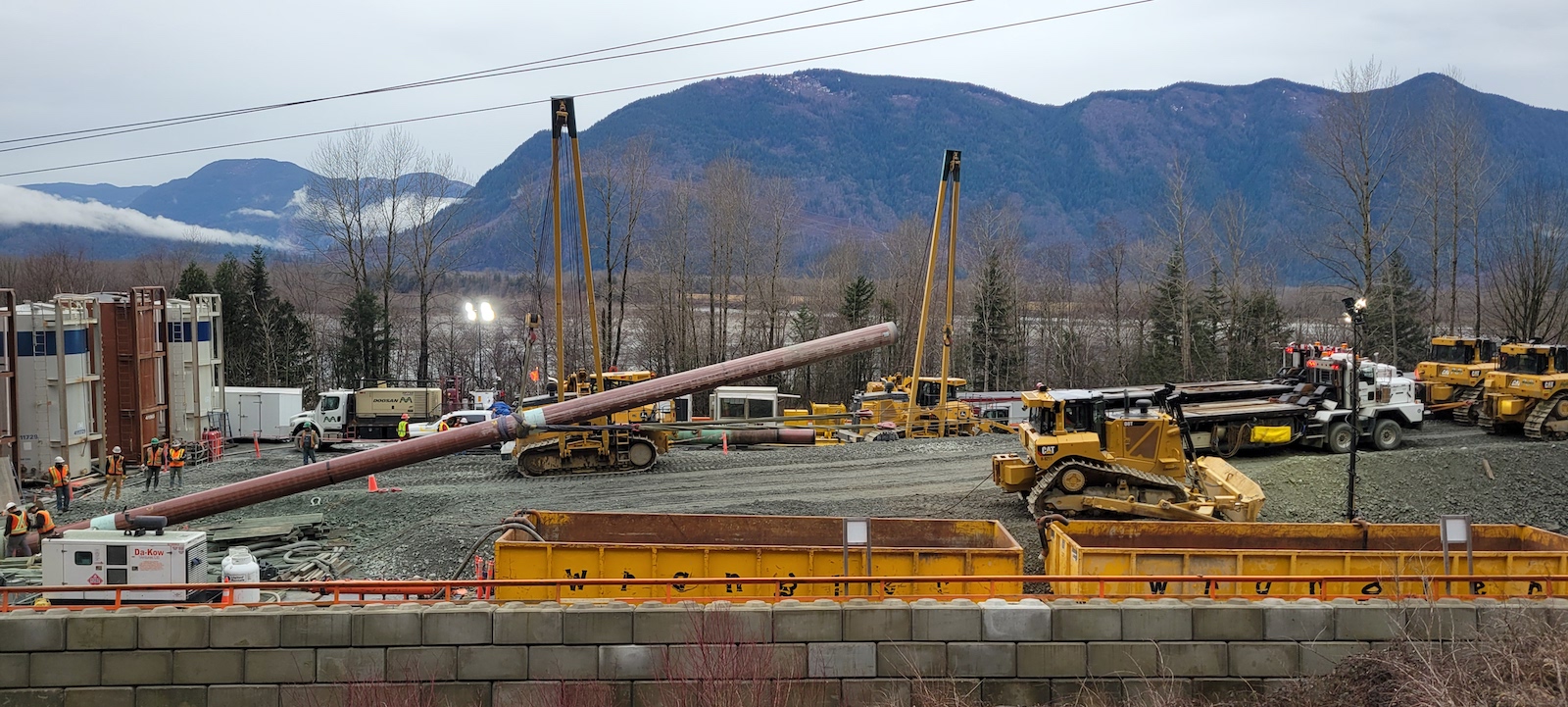 Heavy machinery moves pipeline lengths into place.