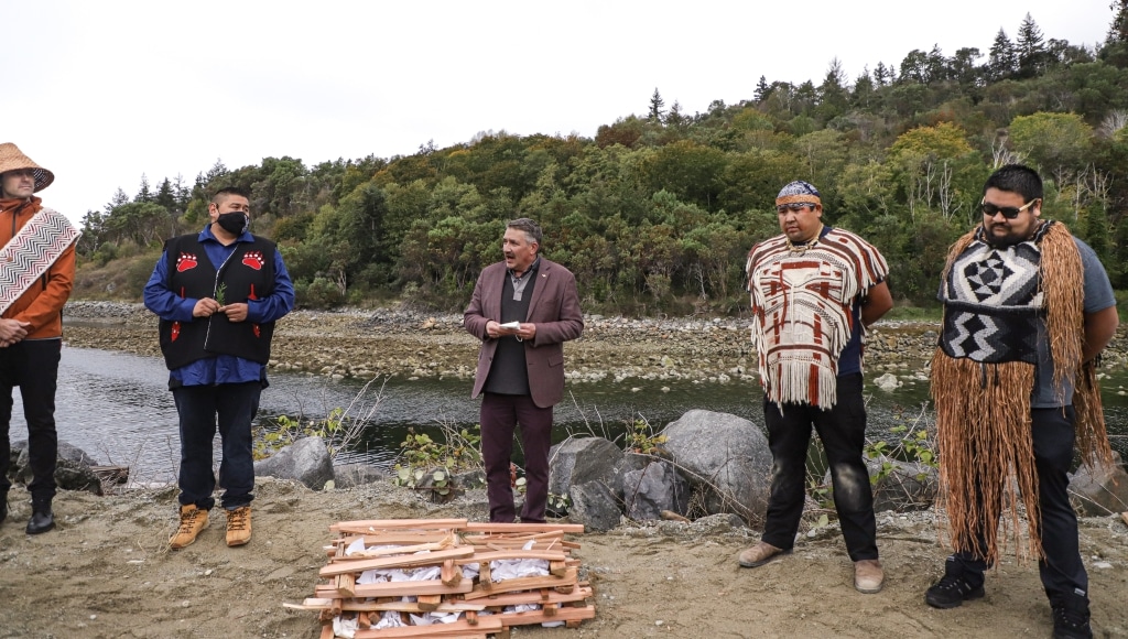 Five people stand next to a river.