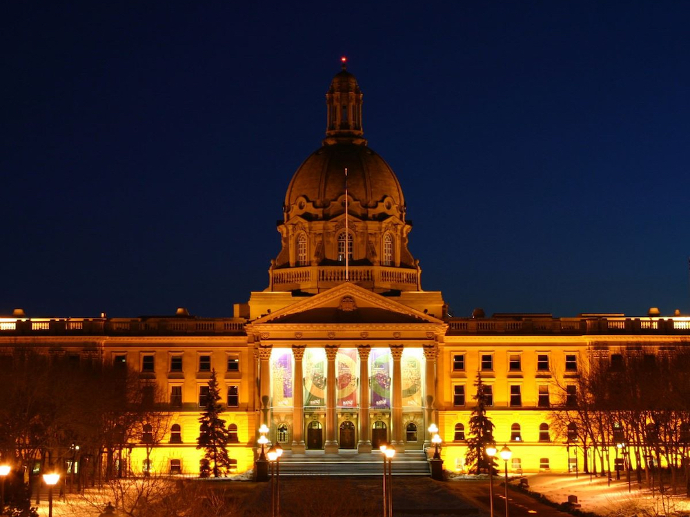 The Alberta legislature building lit up at night.