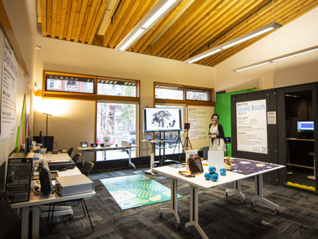 A sound booth and other items are available in a room with a wood-panelled ceiling.