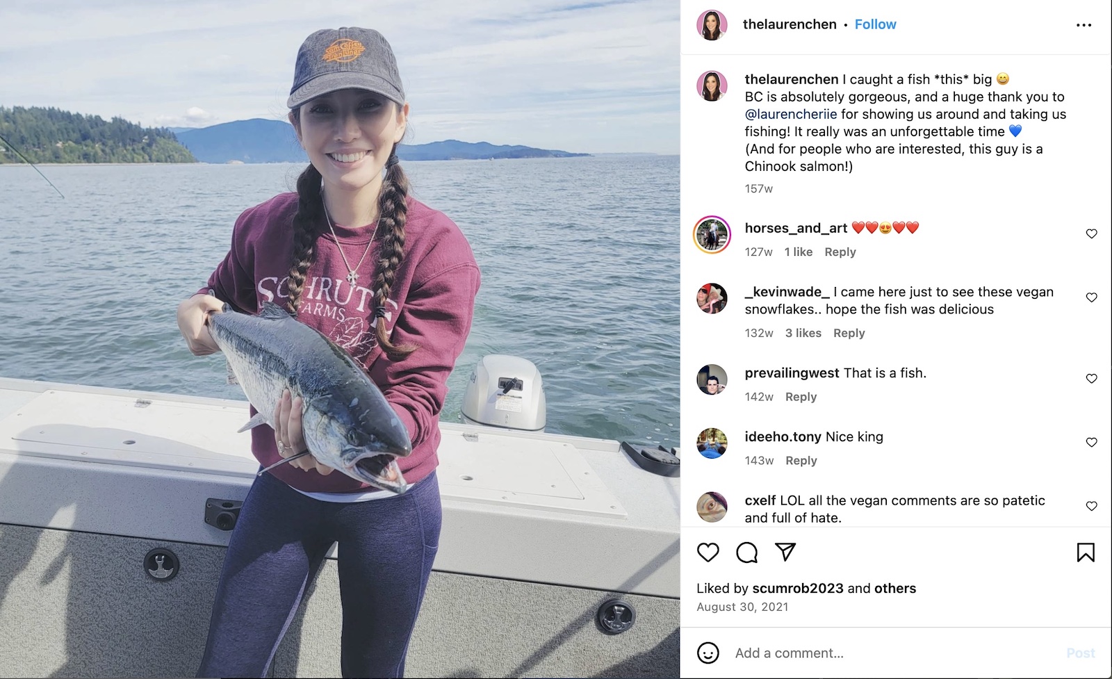 A light-skinned woman with long braids is in a boat, holding a salmon.