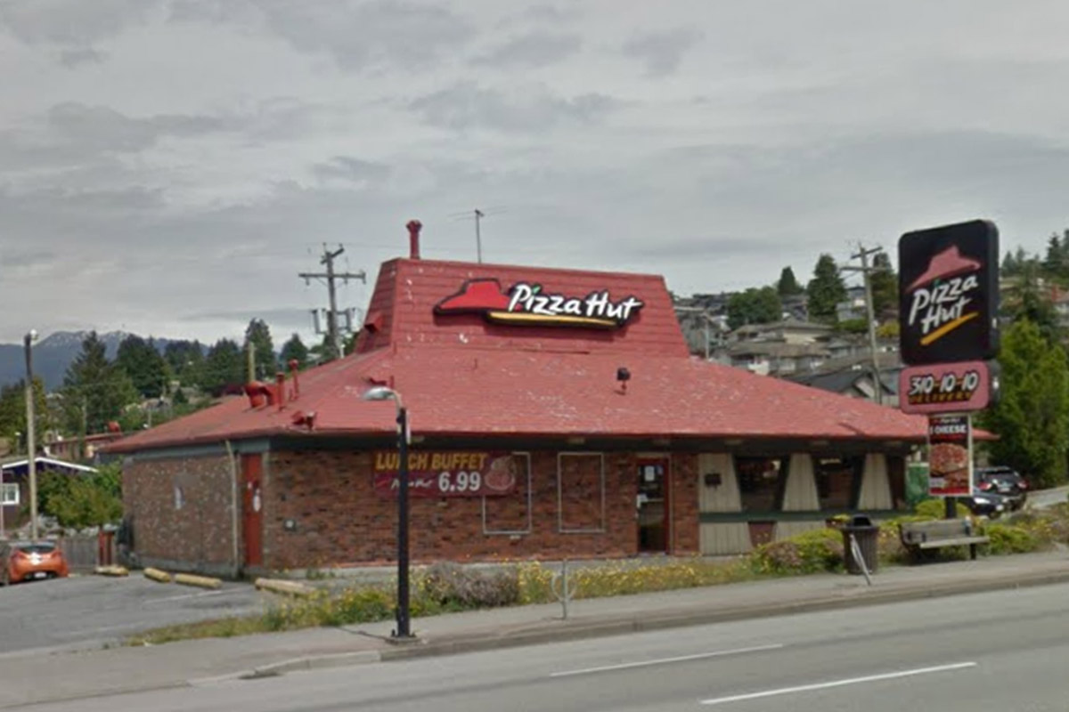 A classic Pizza Hut building with a brick exterior, red roof and Pizza Hut logo on the roof.