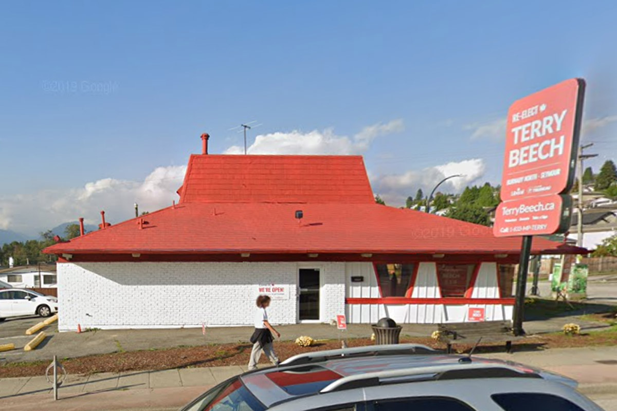 An old Pizza Hut building. The brick base is painted white, and the roof is red.