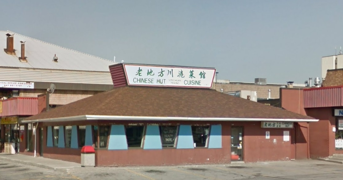 A building shaped like a Pizza Hut has a sign on the roof reading, 'Chinese Hut, Szechuan Peking Cuisine.'
