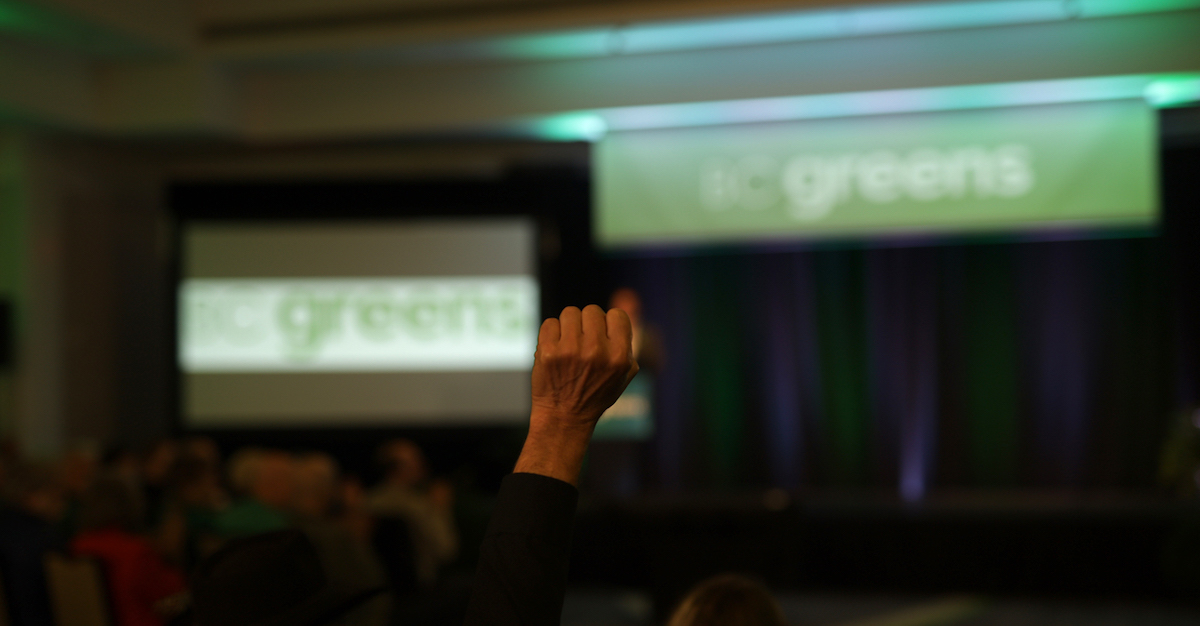 A person holds their fist in the air as Sonia Furstenau concedes her seat.