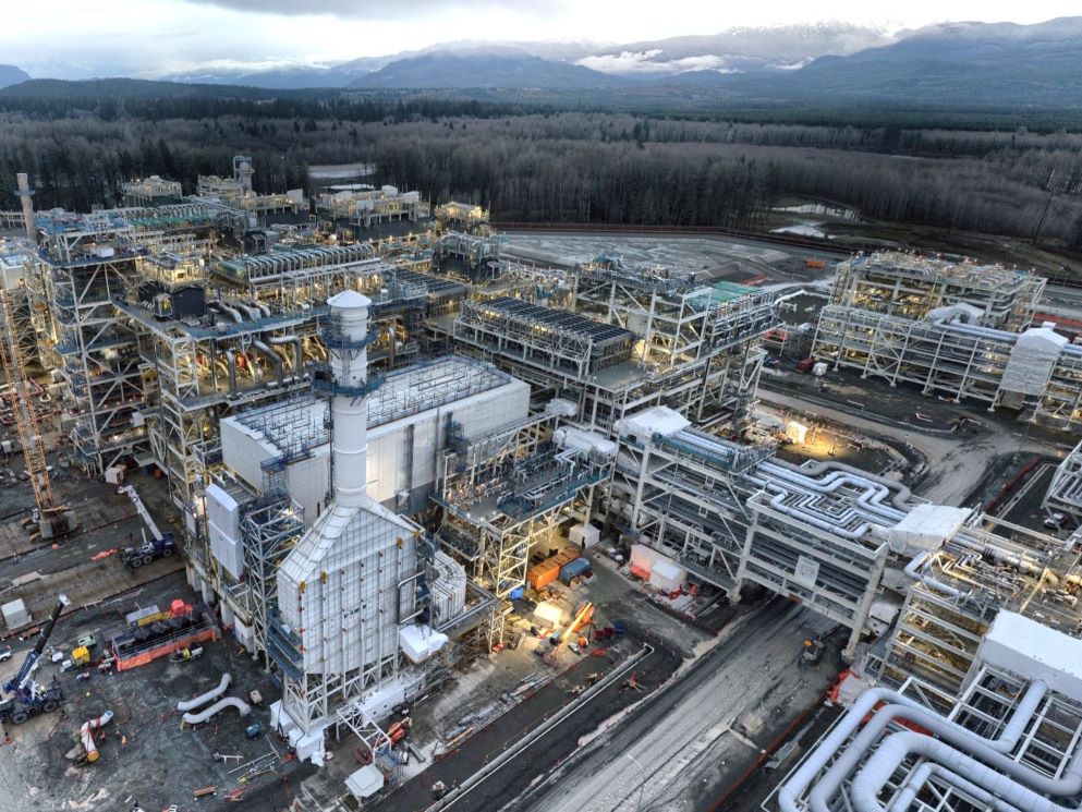 An aerial shot shows a massive LNG plant under construction, with cranes, buildings and networks of pipes.