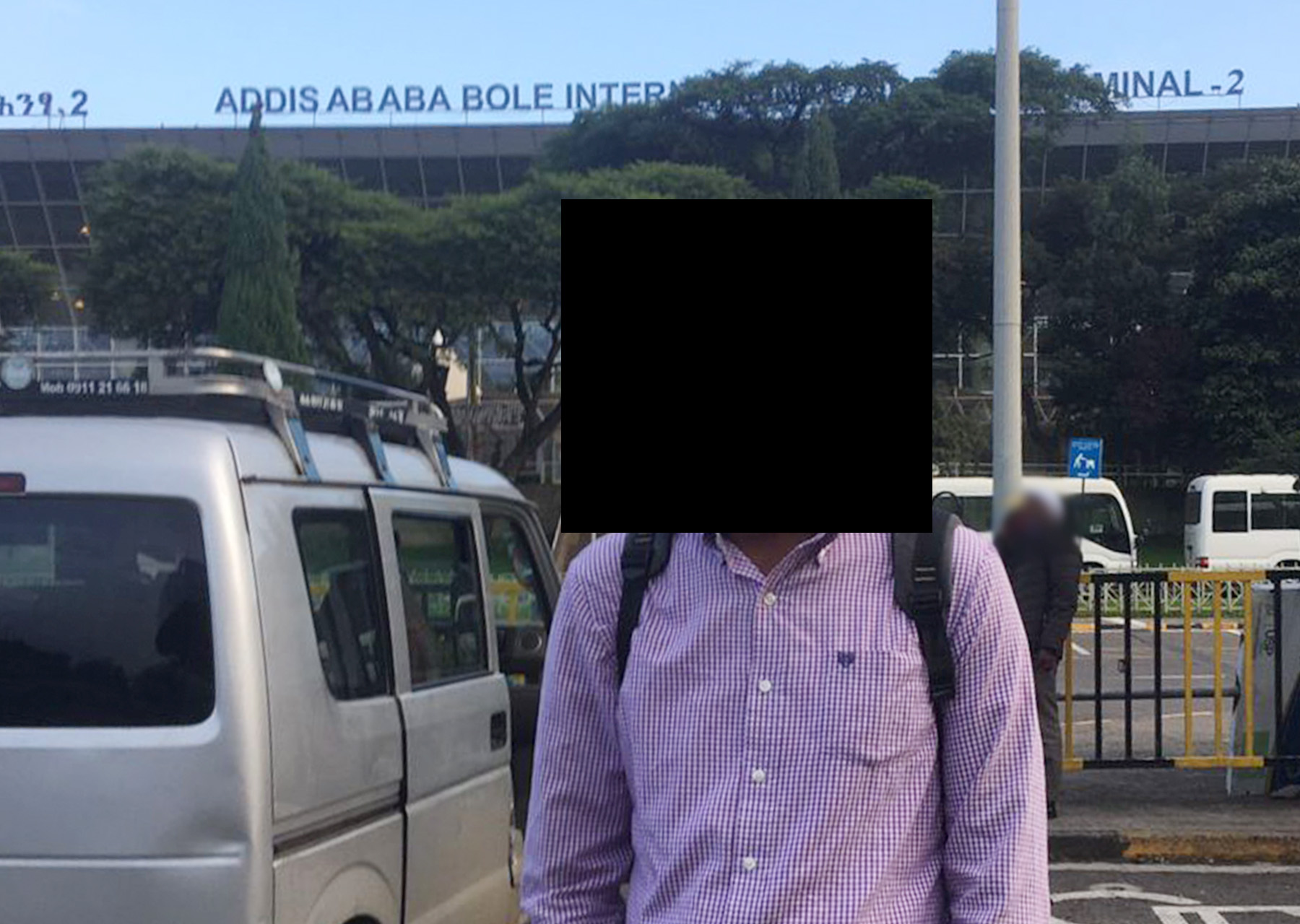 An image of a man standing outside, with his face obscured.