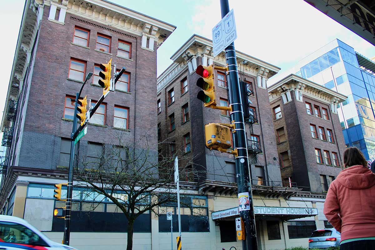 Looking up at a five-storey brick building with ornate decorations around the roofline. The ground is closed and a marquee says 'Student Housing.'