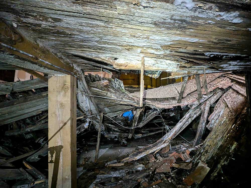 A photo of a room at Dunsmuir House in a state of decay, with large sections of the ceiling collapsed.
