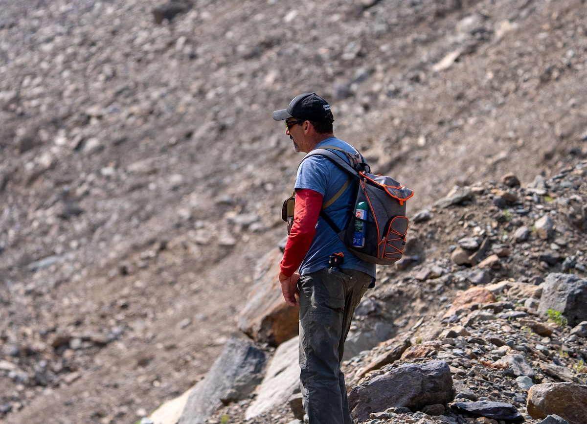 A man stands on the side of a mountain.