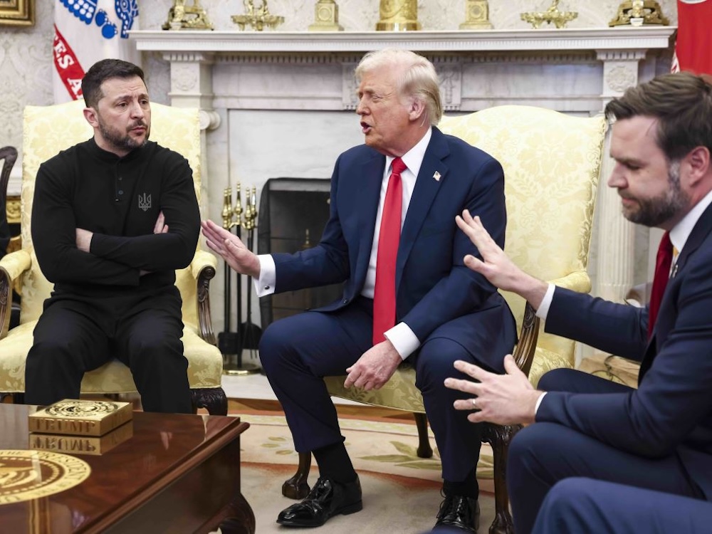 Zelensky, in black, sits in the Oval Office. Donald Trump and JD Vance sit to his left, both looking dismissive and holding up their hands.