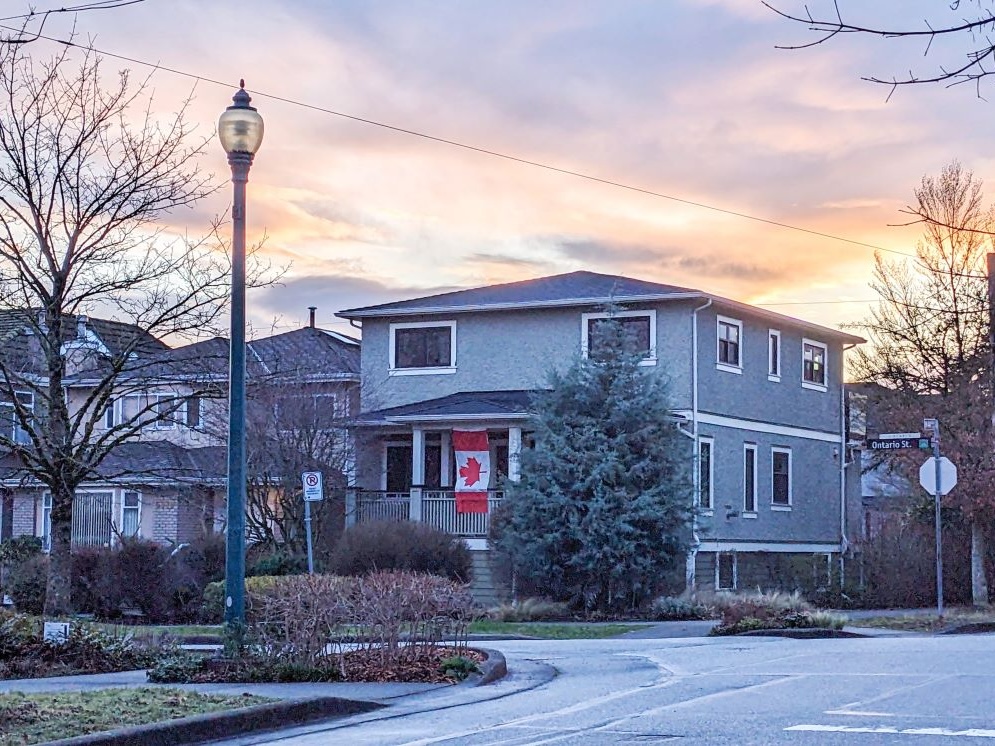 A single-family home displays a Canadian flag hanging above its doorway.