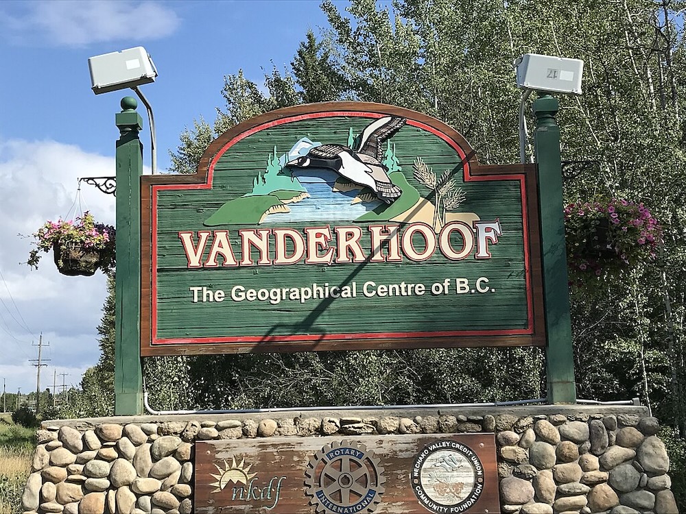 A forest-green town welcome sign reads ‘Vanderhoof, the Geographical Centre of B.C.’