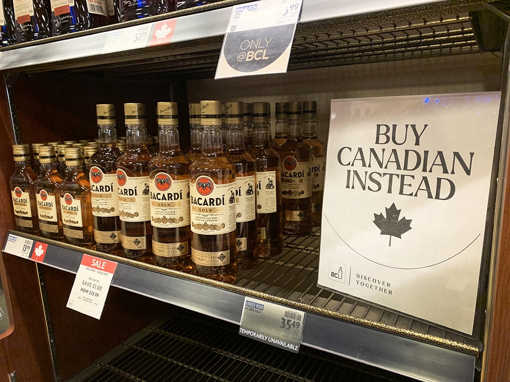 Bottles of Bacardi Gold are labelled with a red maple leaf and sit beside a sign reading, ‘Buy Canadian Instead.’