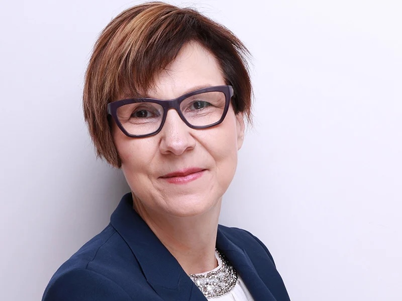 Cindy Blackstock, a middle-aged Gitxsan woman with a brown bob and medium-light skin tone, wears glasses and a blue blazer.