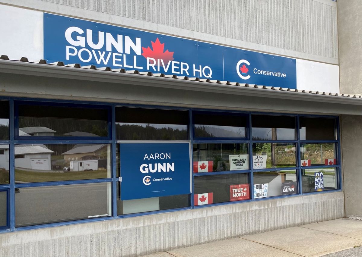The outside of a grey building in Powell River holds signs for Aaron Gunn's Conservative campaign.