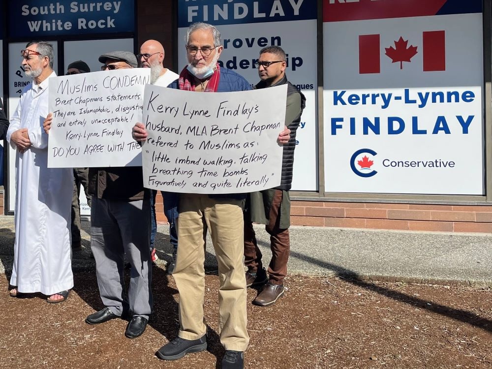 A half-dozen people stand outside MP Kerry-Lynne Findlay&rsquo;s office holding signs that condemn MLA Brent Chapman and seek a response from Findlay.