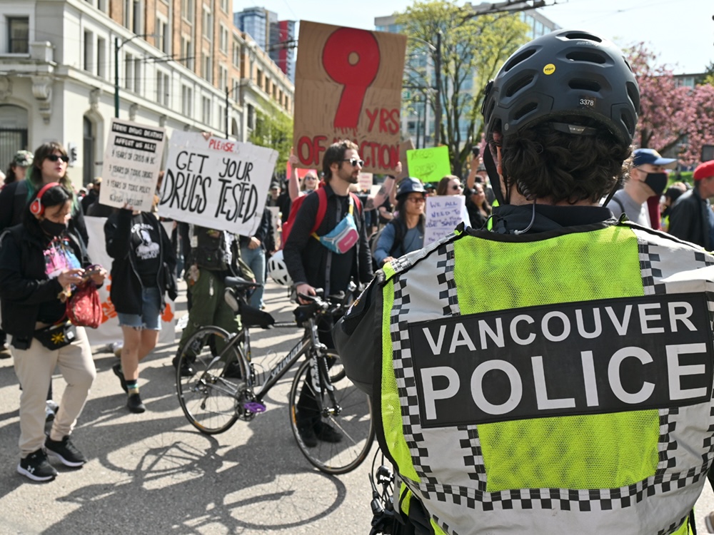 A police officer wears a hi-vis vest reading &lsquo;Vancouver Police&rsquo; at a rally in the Downtown Eastside.