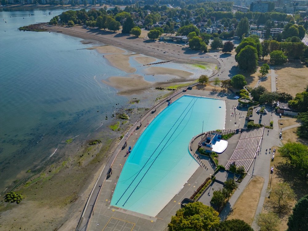 An aerial photo shows oval-shaped Kitsilano Pool, as well as the Showboat stage, the park and beach.