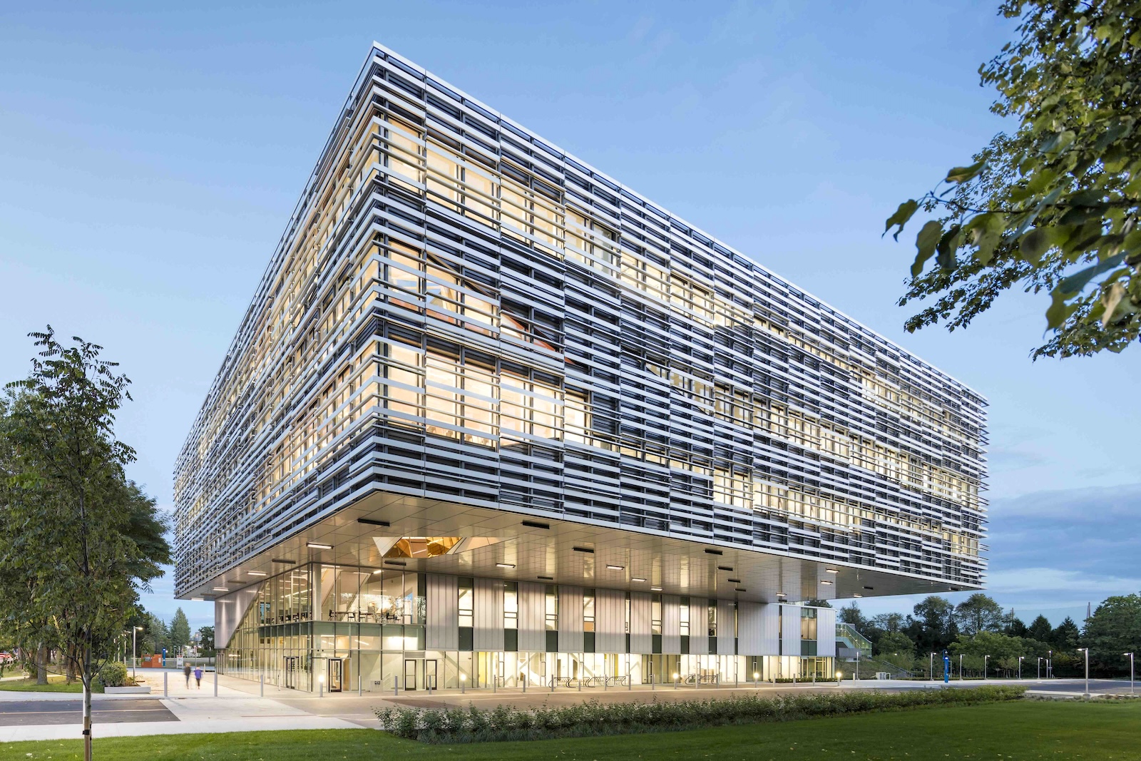 Langara College’s science and technology building at dusk. The contemporary, futuristic building is white with horizontal fixtures across the windows on the upper floors.