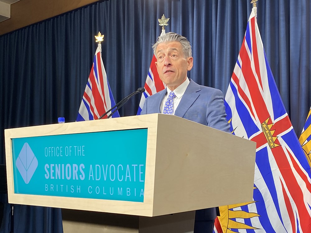 Dan Levitt speaks at news conference. He is an older man with light skin tone and short grey hair. He is wearing a suit and standing behind a lectern.